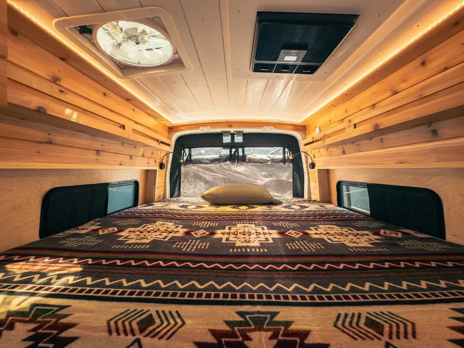 Gemütlicher Schlafbereich im Lonely Cactus 2 Campervan mit Holzverkleidung und großer Liegefläche.