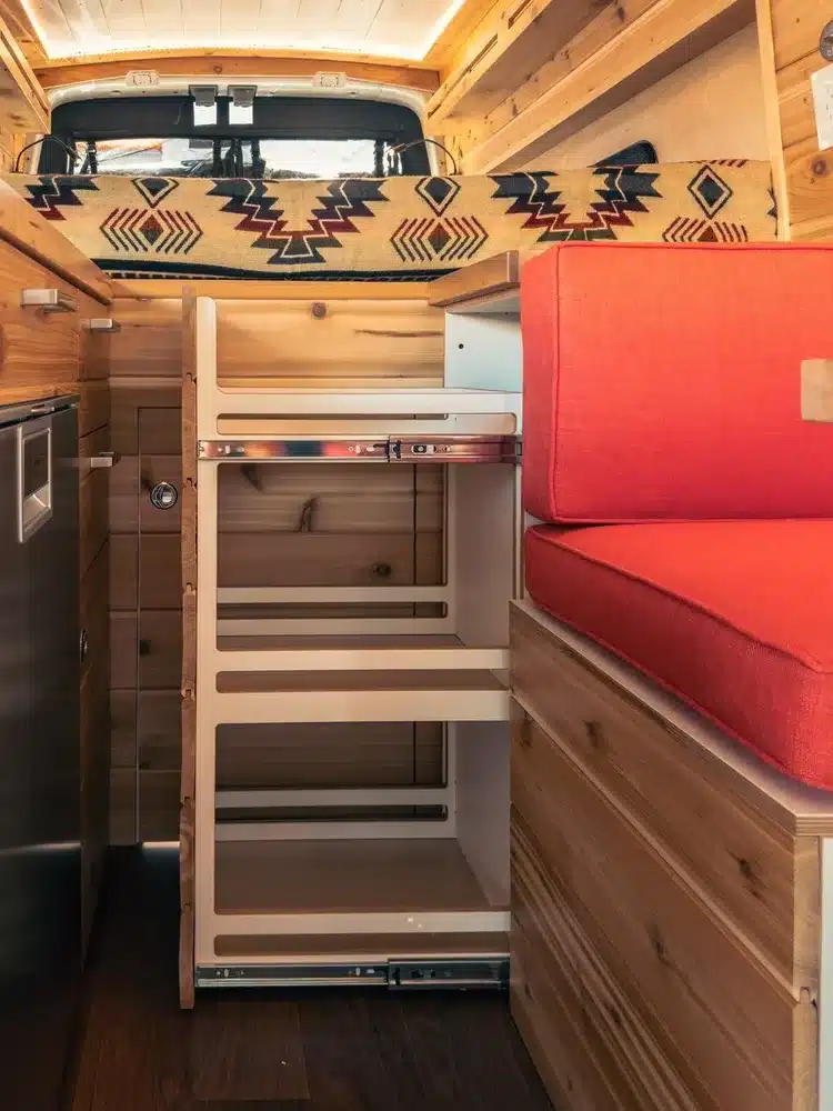 Ausgebauter Innenraum eines Lonely Cactus 2 Campervans mit ausziehbarem Stauraum, Sitzfläche und Holzausbau.