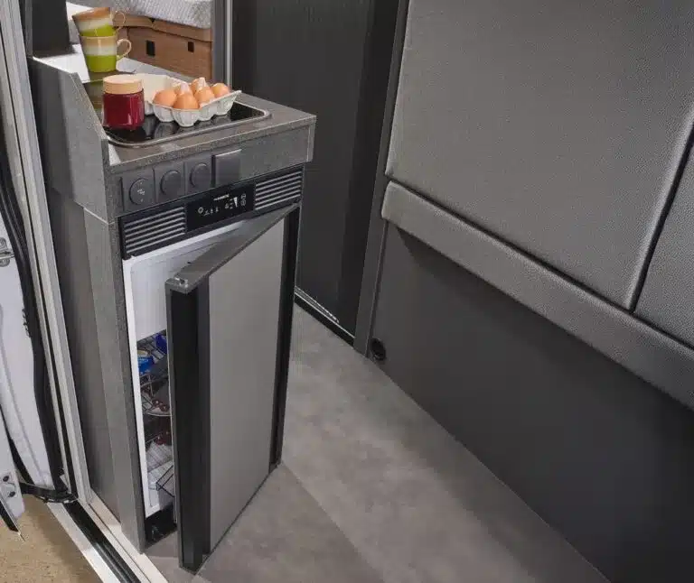 Offener Kühlschrank und Küchenbereich im Malibu Relax Van mit Eiern und Getränken auf der Arbeitsplatte.