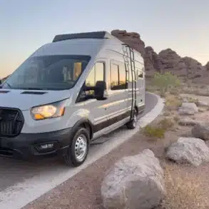 Ford Transit 250 Campervan mit Hochdach auf einer Straße in einer felsigen Wüstenlandschaft