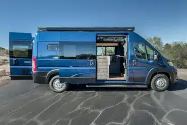 Seitenansicht eines blauen Matt Foley II Campervans mit geöffneten Türen und sichtbarem Innenausbau.