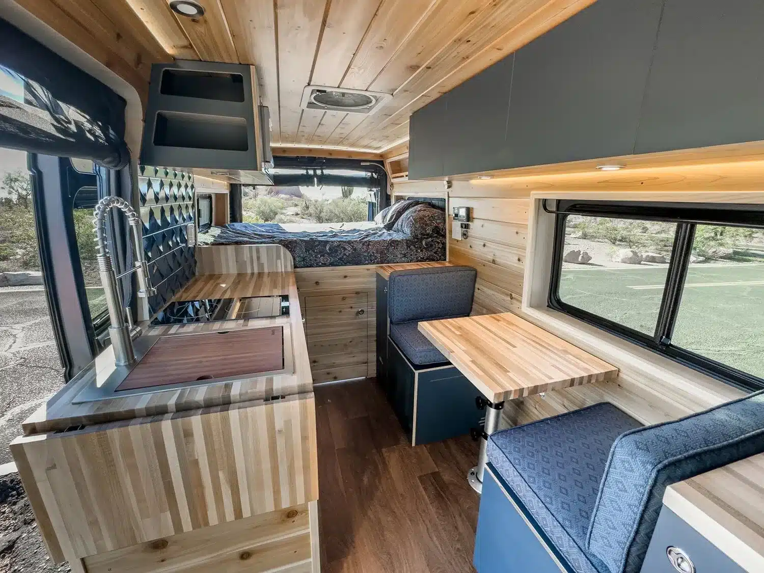 Moderner und aufgeräumter Innenraum des Matt Foley II Campervans mit Küchenzeile, Sitzgruppe und Bett.