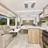 Heller und moderner Innenraum des MPG 2110RB Wohnwagens mit Sofa, Bett, Küchenzeile und großen Fenstern.
