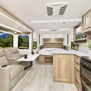 Heller und moderner Innenraum des MPG 2110RB Wohnwagens mit Sofa, Bett, Küchenzeile und großen Fenstern.