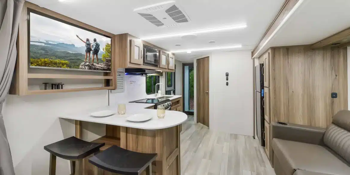 Innenansicht eines MPG 2400PD Travel-Trailers mit Küche, Essbereich, Sofa und hellen Holzmöbeln.