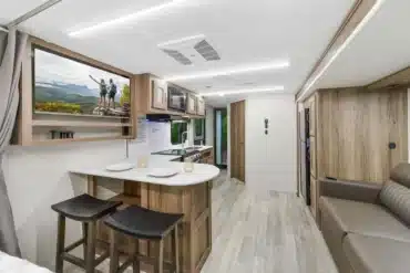 Innenansicht eines MPG 2400PD Travel-Trailers mit Küche, Essbereich, Sofa und hellen Holzmöbeln.