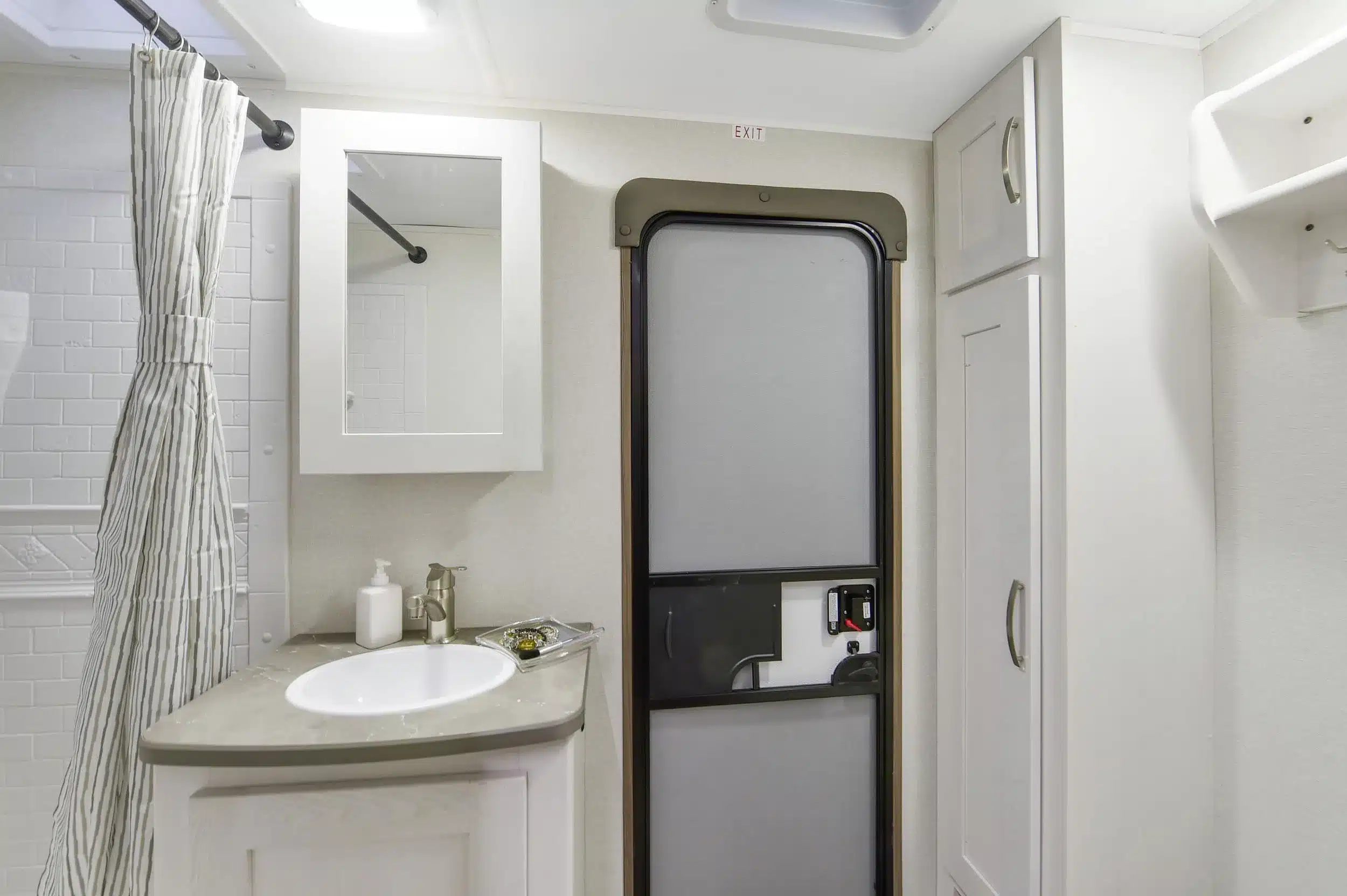 Waschbecken, Spiegelschrank, Dusche und Tür im Badezimmer eines MPG 3310BH Travel Trailer