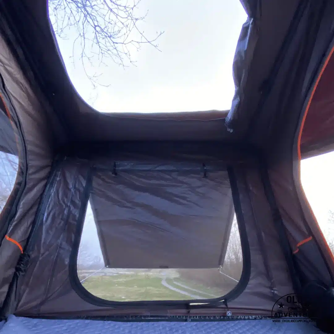 Blick von innen durch das geöffnete Erkerfenster des OLC140ALU 2.0 Dachzelts mit viel Kopffreiheit.