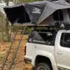 Hartschalen-Dachzelt OLC150Alu Hybrid von OLC Adventure auf einem Pickup mit aufgebauter Teleskopleiter im Wald.