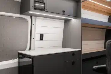 Innenansicht der Küchenzeile und Stauraum im Outreach Van mit moderner Möblierung und Stromversorgung