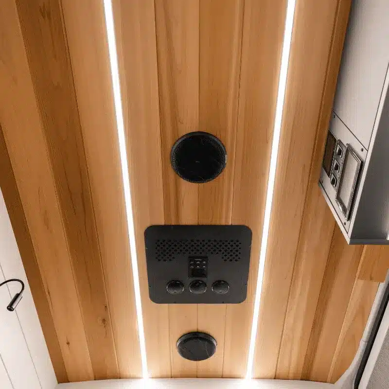 Detailaufnahme der Holzdecke mit LED-Lichtleisten und Steuerpanel im Innenraum eines Outreach Vans