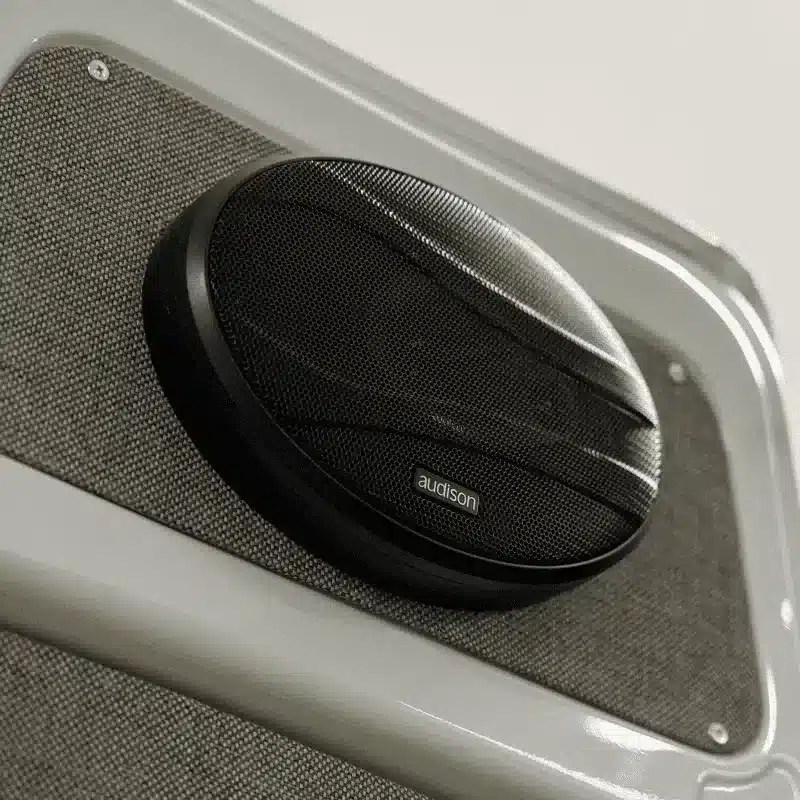 Detailansicht eines eingebauten Audison-Lautsprechers in einer Campersitzwand.