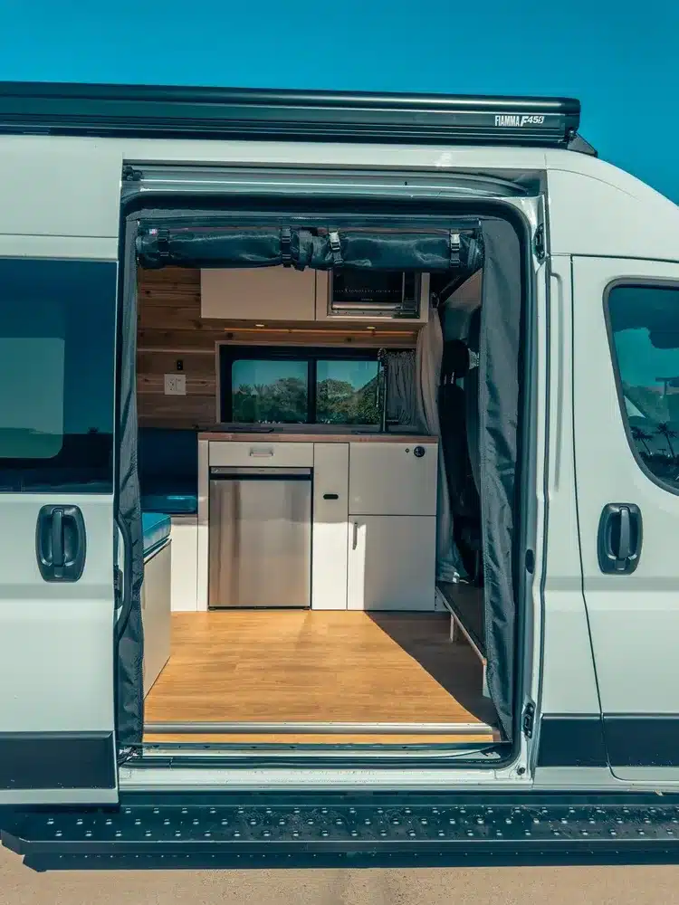 Geöffnete Seitentür des RAM Promaster 2500 Campervan, zeigt Küche und Innenraum