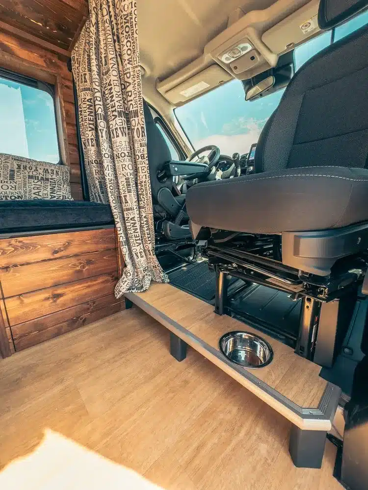 Blick in den vorderen Wohnbereich eines ausgebauten Ram Promaster 2500 mit Holzverkleidung, Sitzbank und integriertem Hundenapf