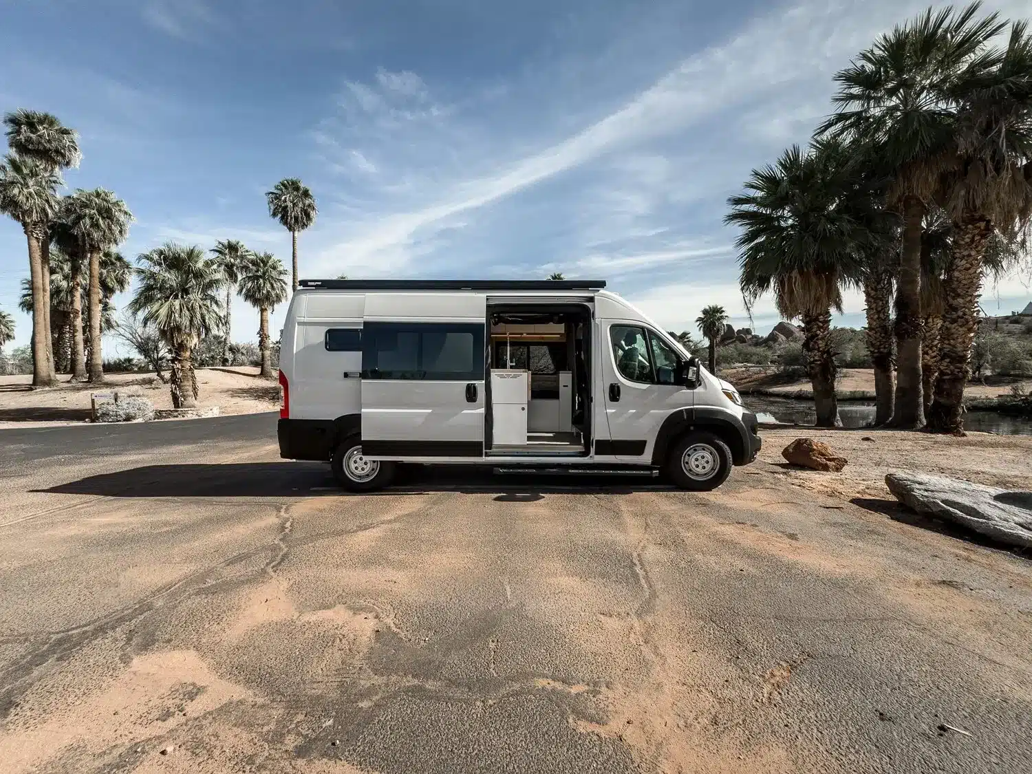 Ram Promaster Kastenwagen als Camper in San Diego mit geöffneter Schiebetür und Palmen im Hintergrund