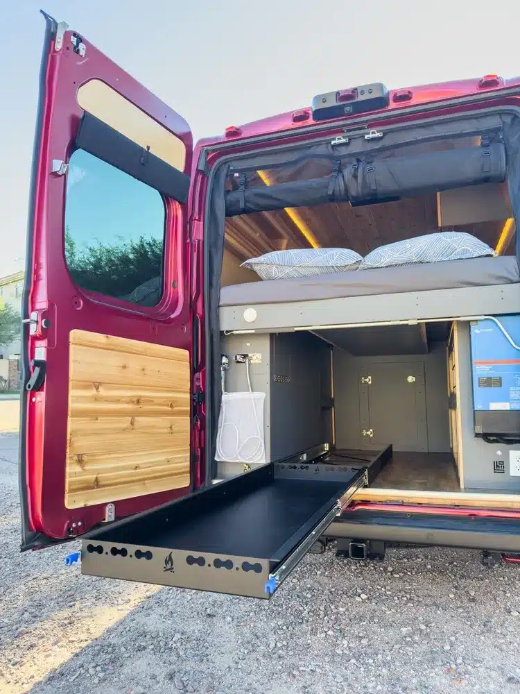 Heckansicht des Red Rover Campervans mit ausgezogenem Stauraum und Bett.