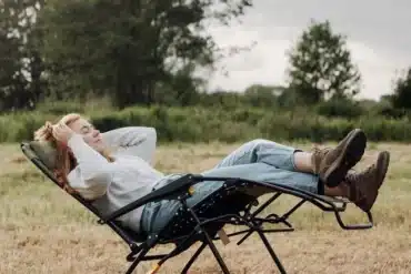 Person entspannt auf einem verstellbaren Relax Campingstuhl mit Fußteil im Freien