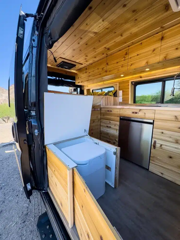 Ausziehbare Trenntoilette in einem Kastenwagen mit Innenausbau aus Holz.