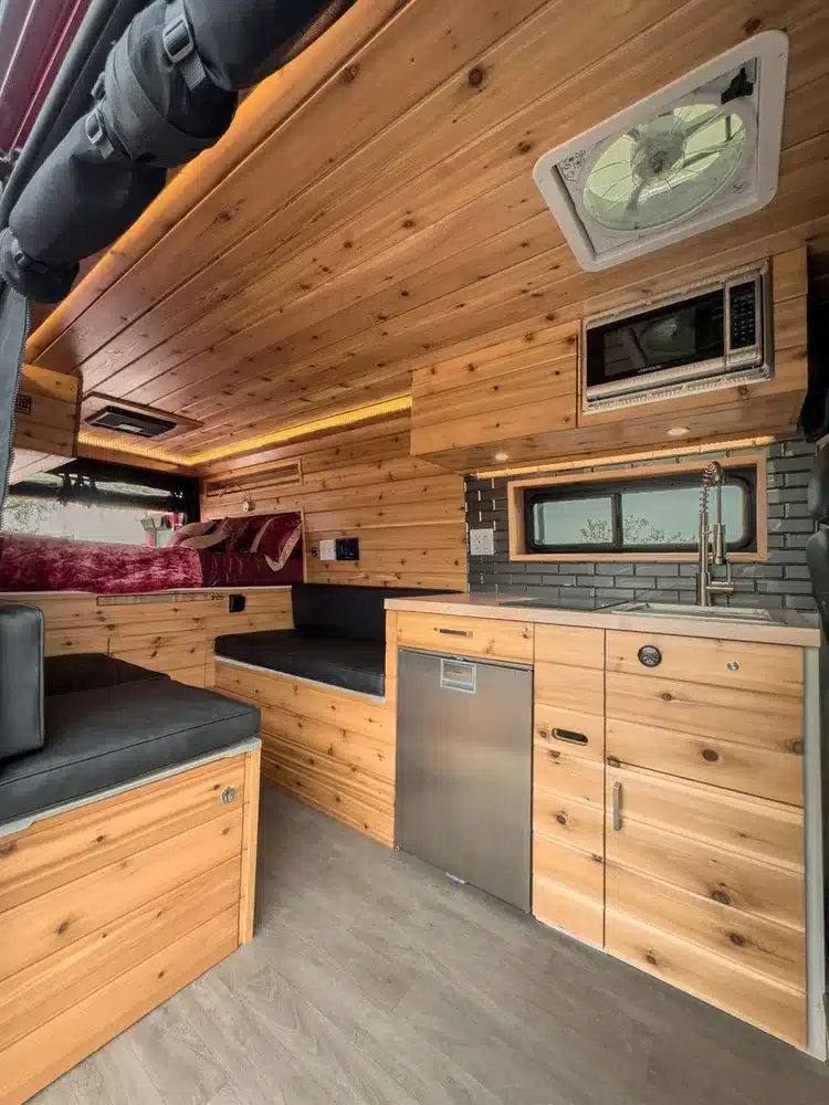 Innenraum eines ausgebauten Kastenwagens Sapho auf Basis des RAM Promaster 3500 mit hochwertiger Holzausstattung, Küche und Sitzgruppe.