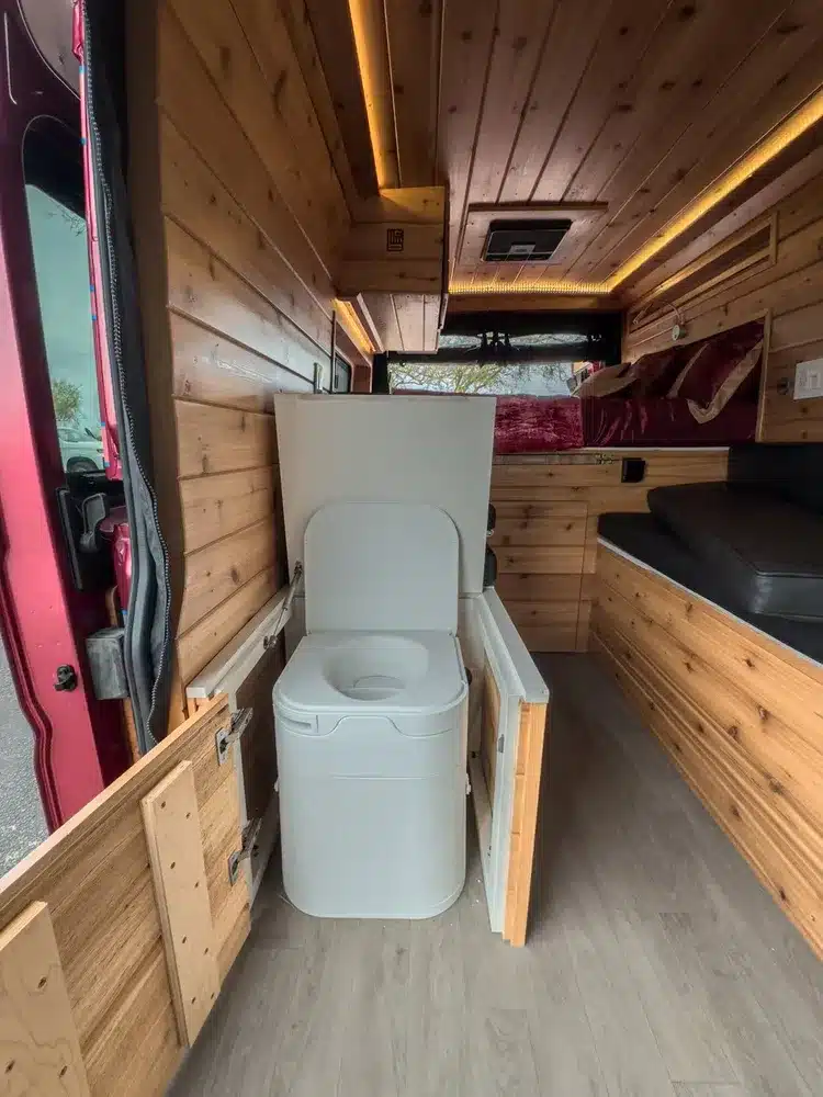 Komposttoilette im mobilen Schrankauszug eines ausgebauten Kastenwagens mit Holzverkleidung.