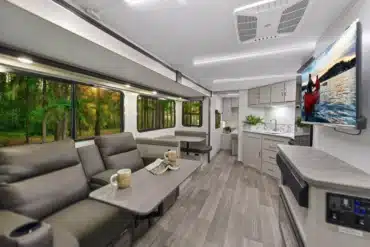 Innenansicht des Shadow Cruiser 261RB Wohnanhängers mit gemütlicher Sitzgruppe, Küche und Fernseher.