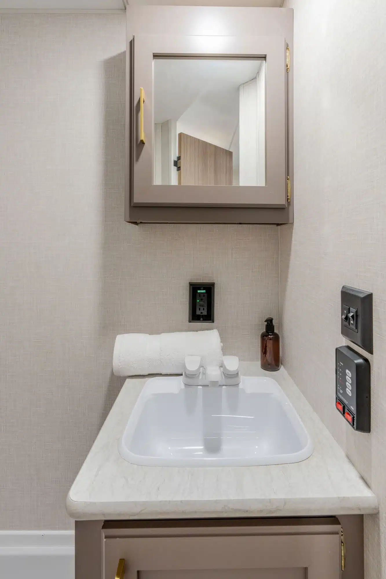 Waschbecken mit Spiegelschrank im Badezimmer eines kompakten Reise-Trailers Sportsmen Classic