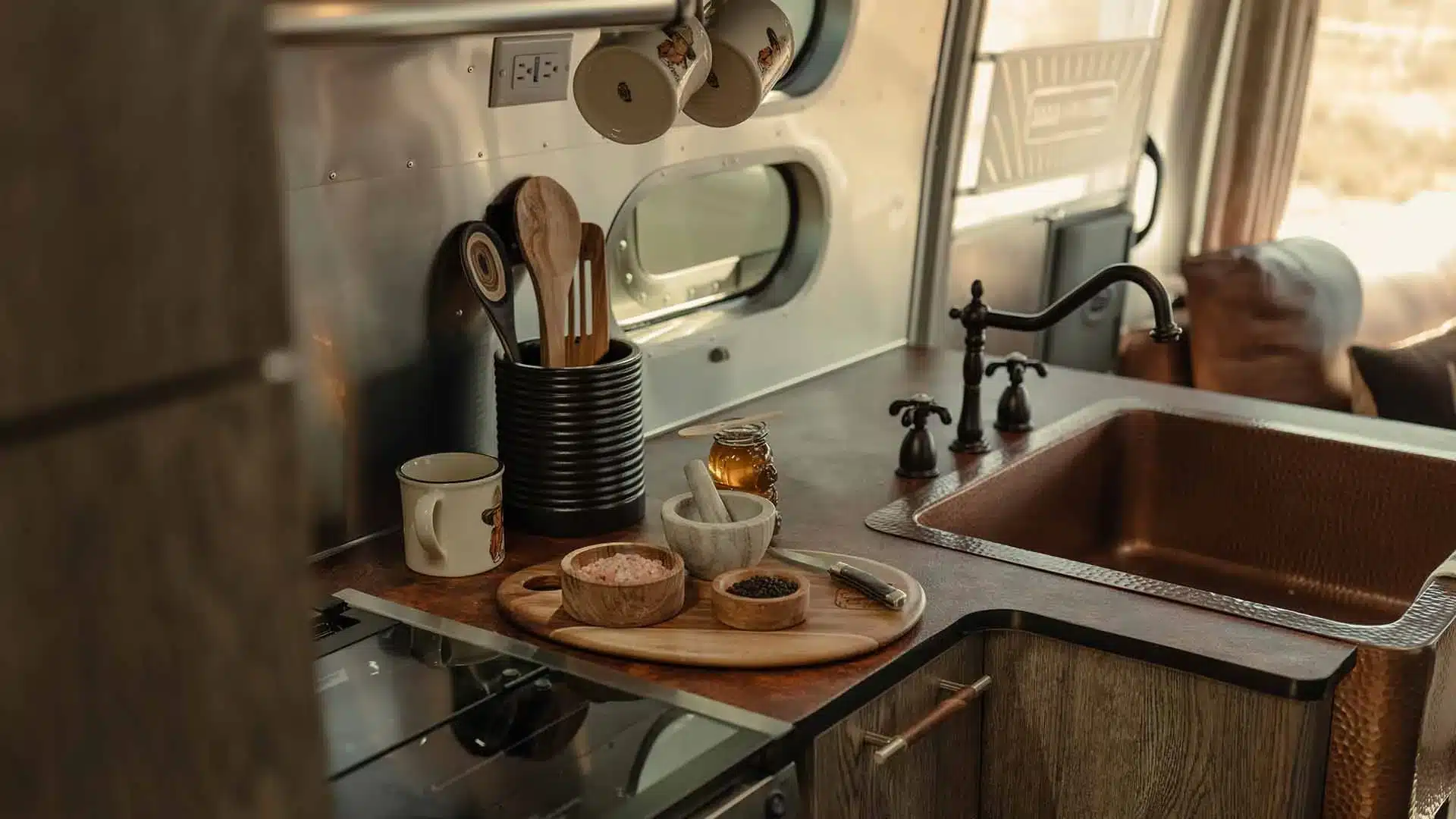 Küchenbereich im amerikanischen Travel Trailer mit gehämmerter Kupferspüle und Western-inspiriertem Interieur.