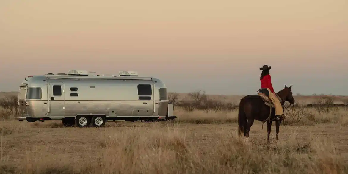 Stetson + 6666 Special Edition Travel Trailer mit Cowboy auf Pferd in weiter Prärie, Sonnenuntergang, Western-Stimmung
