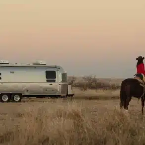 Stetson + 6666 Special Edition Travel Trailer mit Cowboy auf Pferd in weiter Prärie, Sonnenuntergang, Western-Stimmung