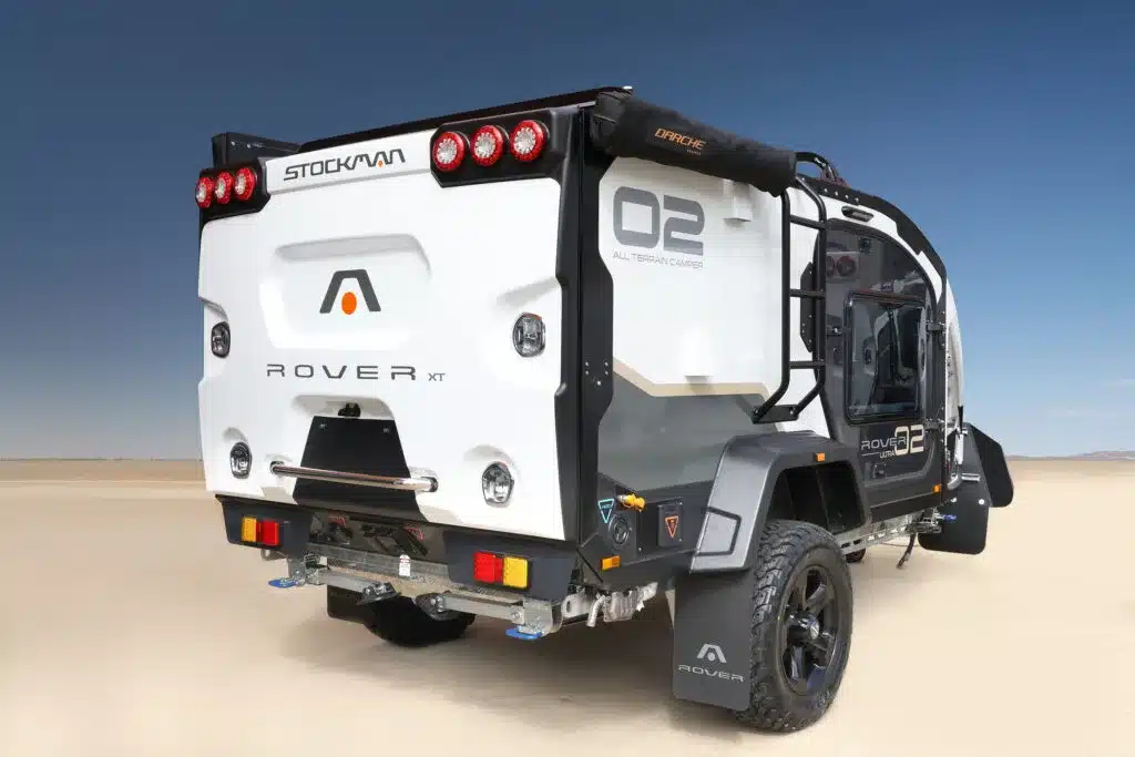 Heckansicht des Stockman Rover 02 Ultra Campers mit großem Stauraum und Offroad-Ausstattung auf sandigem Untergrund.