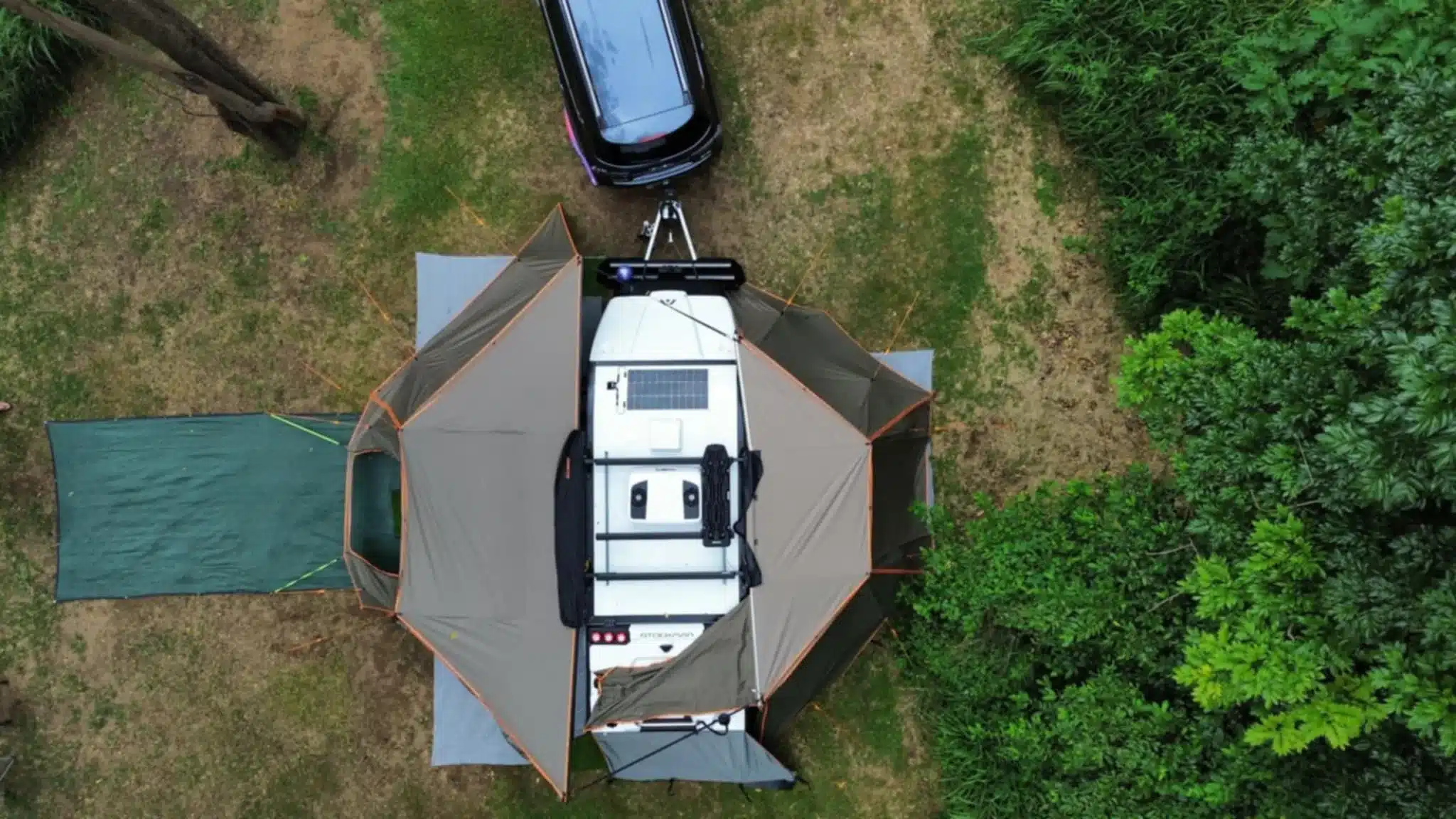 Luftaufnahme eines Stockman Rover 02 Offroad-Pod-Campers mit vollständig ausgeklappten Markisen neben einem Zugfahrzeug auf einer Wiese