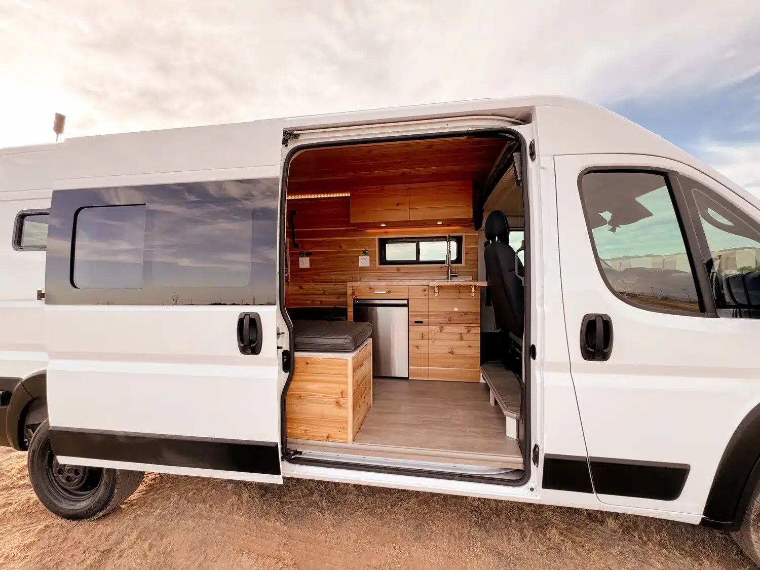 Innenansicht eines ausgebauten THE 505 RAM Promaster Camper Vans mit Holzvertäfelung, Küche und Sitzgelegenheit