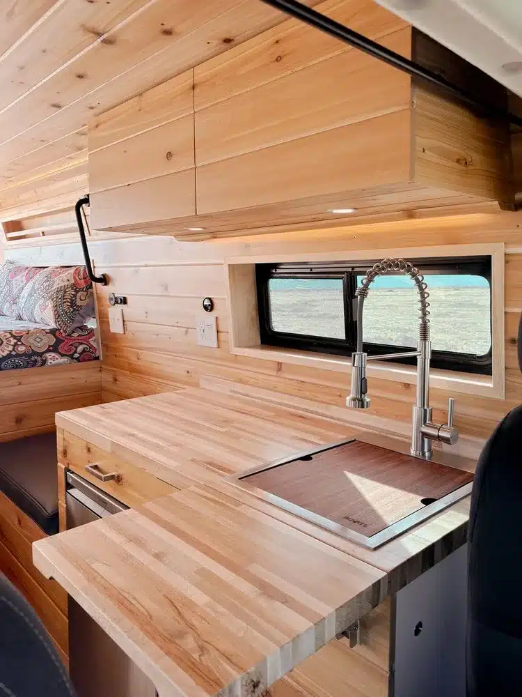 Küchenzeile mit ausziehbarer Arbeitsplatte, Spüle und modernen Armaturen im THE 505 RAM Promaster Camper Van