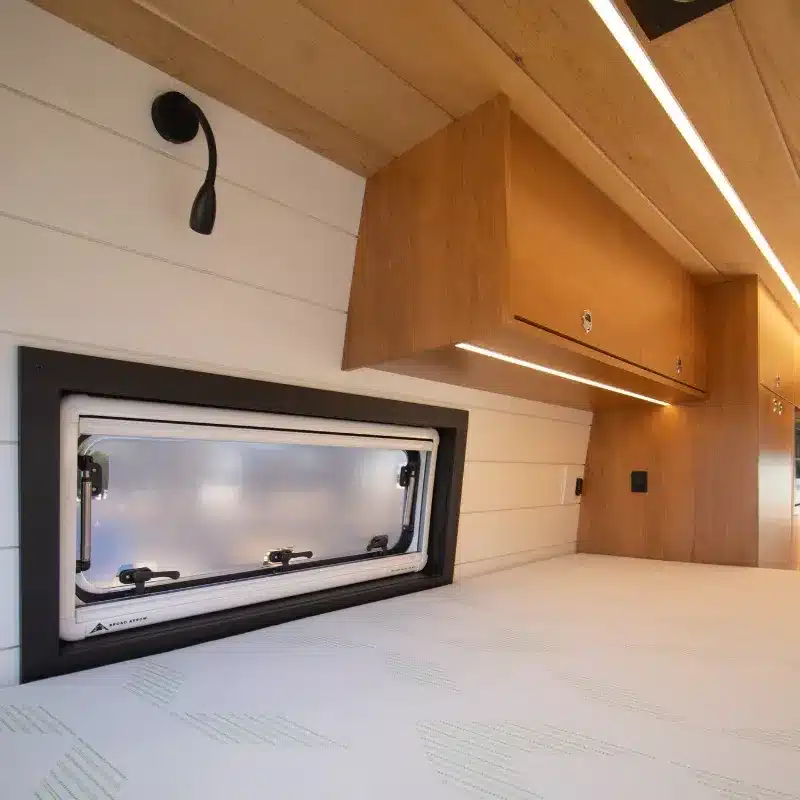 Innenraum des Mercedes Sprinter 170 Campervans mit Bett, Fenster und Holz-Staufächern