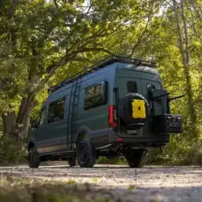 Der grüne Mercedes Sprinter 2500 mit Offroad-Umbau und umfangreichen Trägersystemen in natürlicher Umgebung.