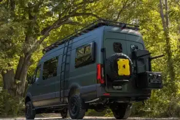 Der grüne Mercedes Sprinter 2500 mit Offroad-Umbau und umfangreichen Trägersystemen in natürlicher Umgebung.