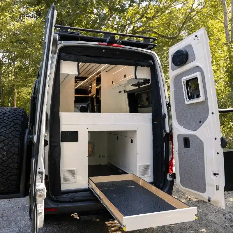Offene Heckklappe eines ausgebauten Mercedes Sprinter The Yoho mit ausziehbarem Stauraum und hochwertigem Innenausbau
