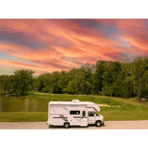 Thor Chateau 2026 Wohnmobil vor Bäumen und See unter farbenfrohem Abendhimmel