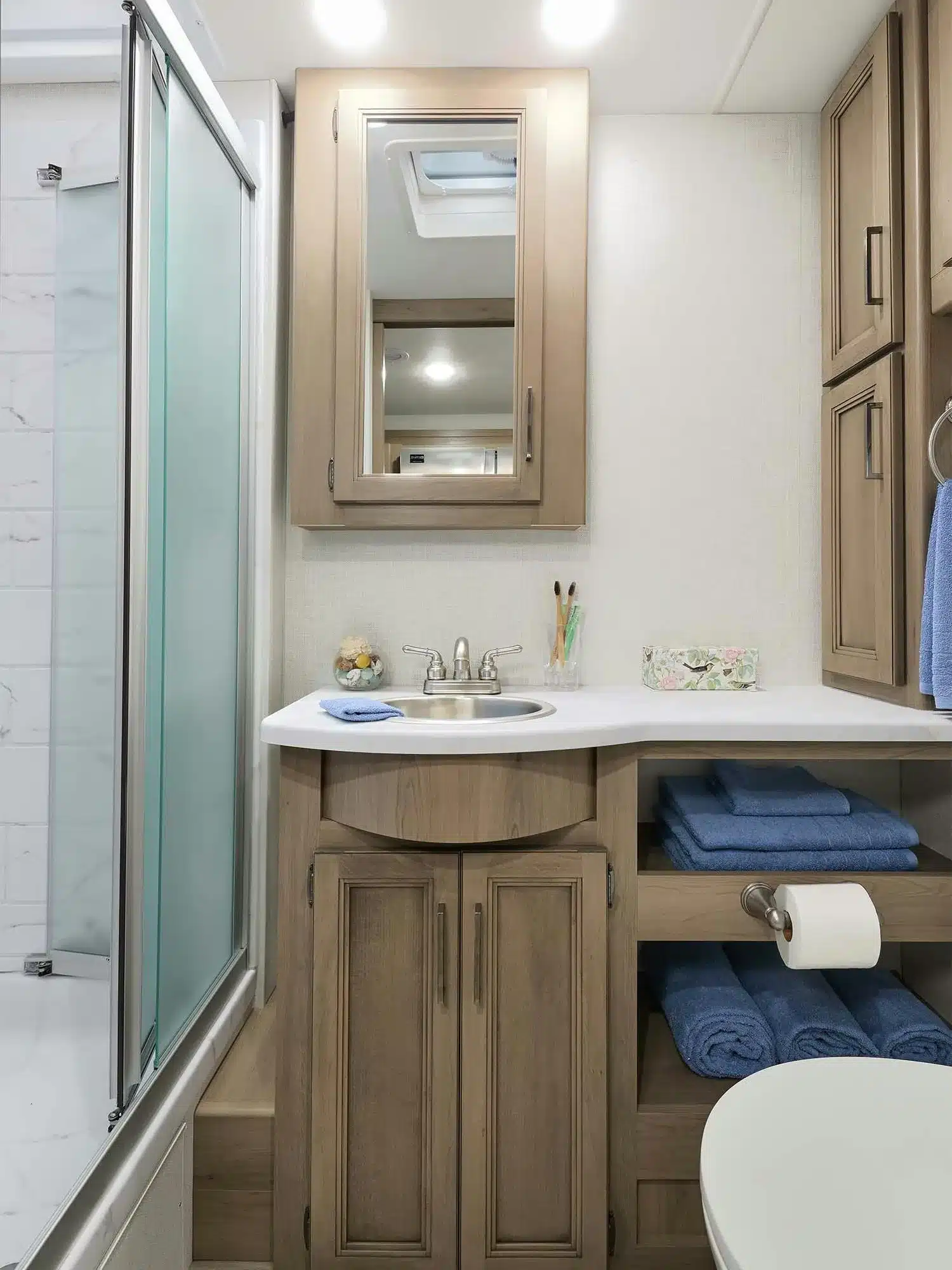 Badezimmer mit Holzschränken, Spiegel, Waschbecken und Dusche im Thor Hurricane 2026 Wohnmobil