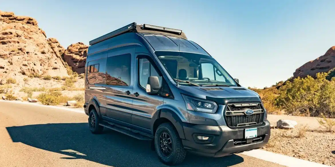 Trinity Ford Transit Trail Camper Van auf einer Straße mit Felsen im Hintergrund