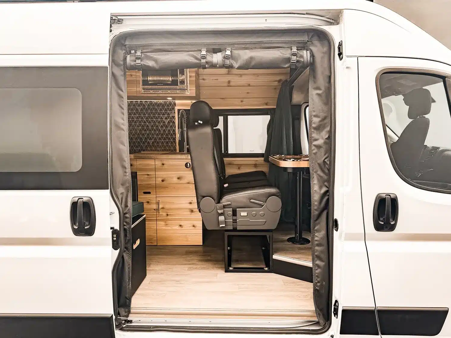 Offene Schiebetür eines ausgebauten RAM Promaster 2500 High Roof Vans mit Sitzbank und Holzausbau