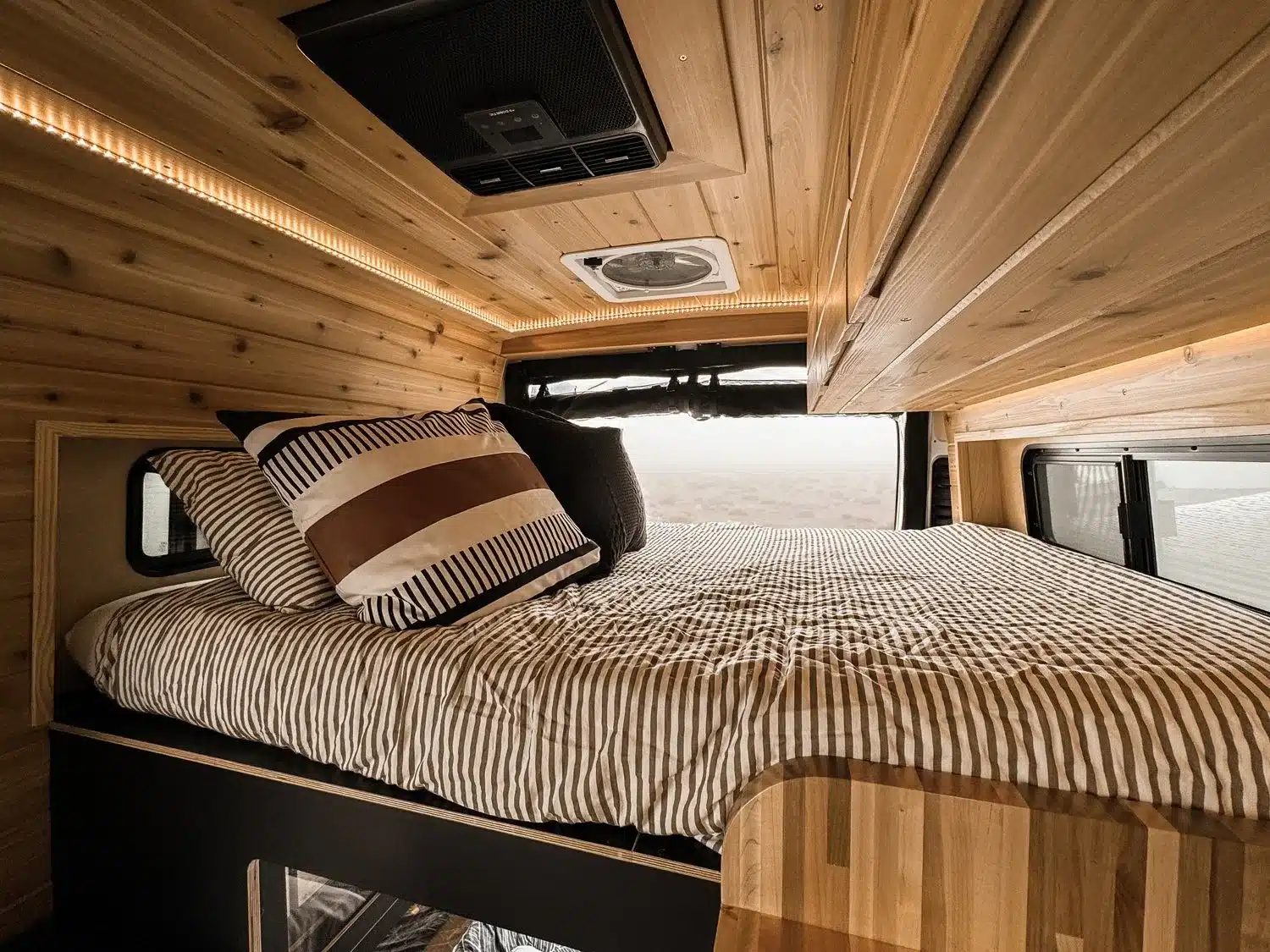 Schlafbereich und Innenausbau aus Holz im V’IBE RAM Promaster 2500 Campervan mit LED-Beleuchtung