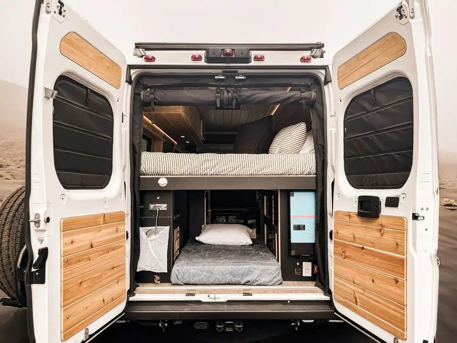 Offene Hecktüren eines V’IBE RAM Promaster 2500 High Roof mit ausgebautem Schlaf- und Stauraumbereich aus Holz und modernen Komponenten.