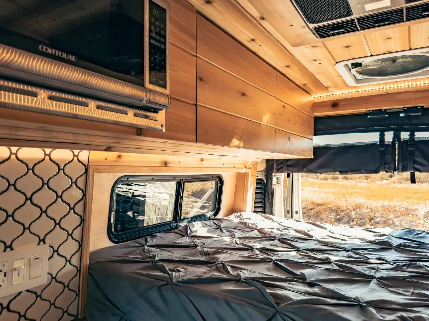 Schlafbereich, Oberschränke und Mikrowelle im Innenraum eines Vandiamo Kastenwagen-Campers