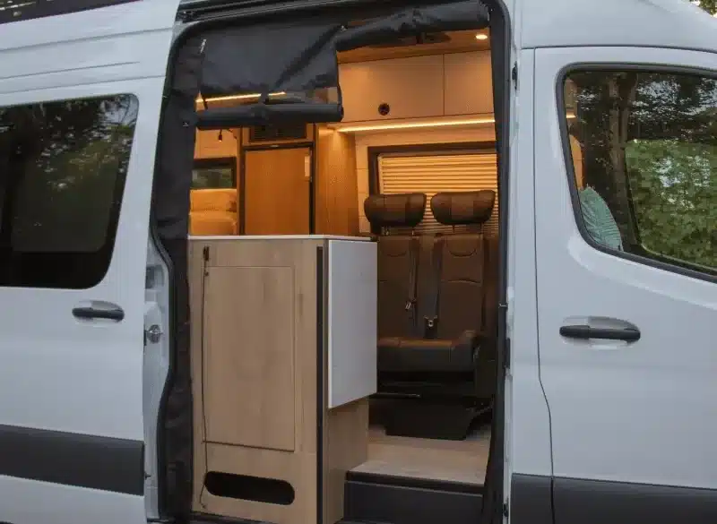 Geöffnete Schiebetür eines Waterton Campervans mit sichtbarer Sitzbank und Küchenmodul