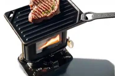 Winnerwell Petroleum Feuerkocher mit gusseiserner Grillplatte und gegrilltem Steak, Flamme sichtbar