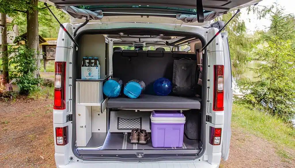Offener Heckstauraum eines Yucon 55 SB FEVER Kastenwagens mit Sitzbank, Schränken und Campingausrüstung.