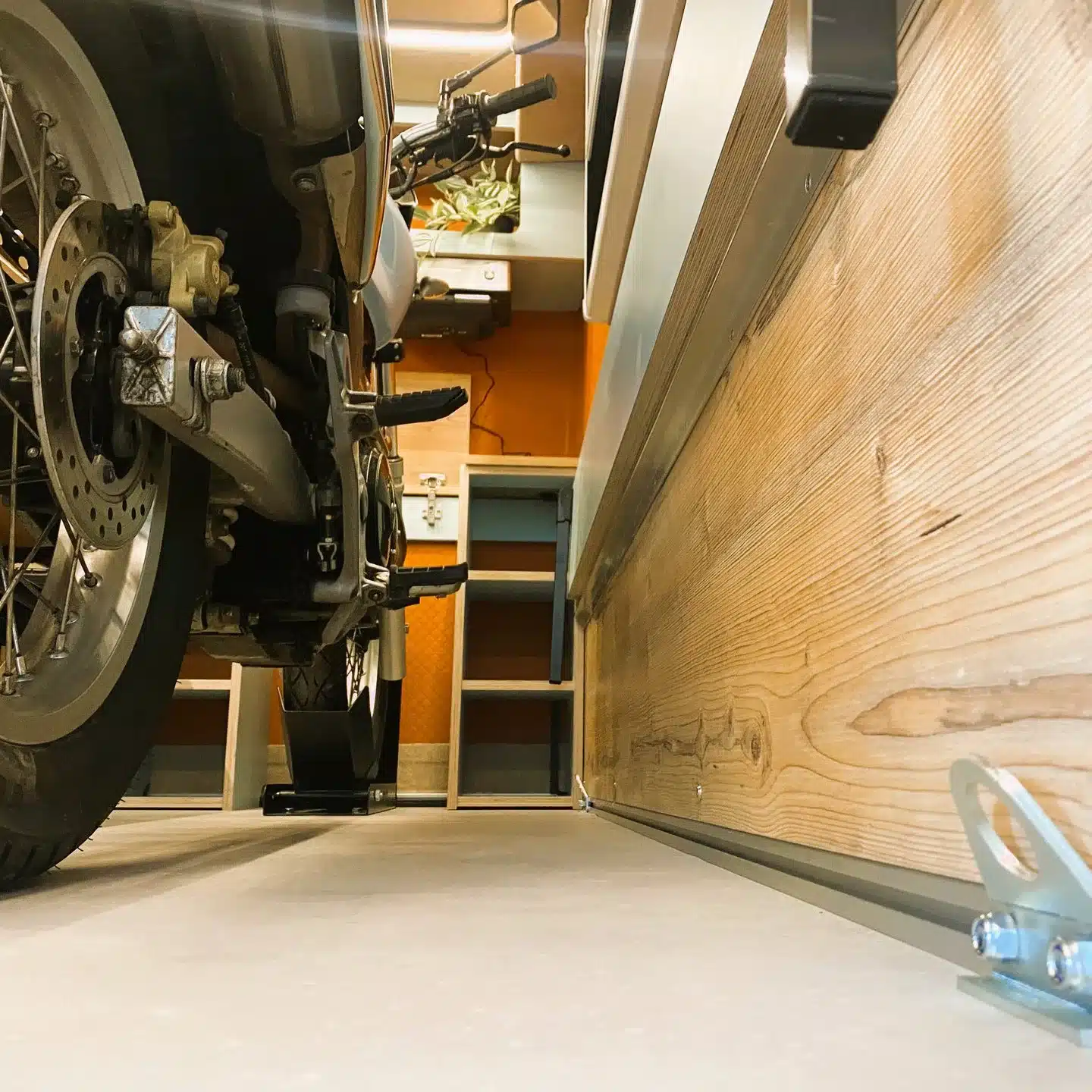 Motorrad steht in der großzügigen Heckgarage eines kompakten Wohnwagens, Detailansicht von innen