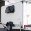7even50 Two Mini-Camper-Anhänger mit geöffnetem Kofferaufbau und Seitenfenster auf einem Hof