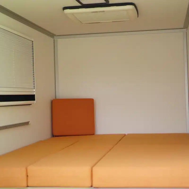 Innenansicht des 7even50 Two Mini-Camper-Anhängers mit aufgeklappter Liegefläche und Polstern